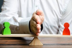 A man divides with his palm two figures of people of opponents on the scales