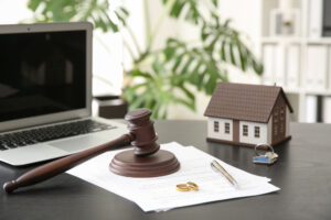 Rings with decree of divorce, judge gavel and house model on table