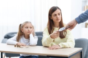 Alimony. Man giving money to his ex-wife and daughter at home, closeup